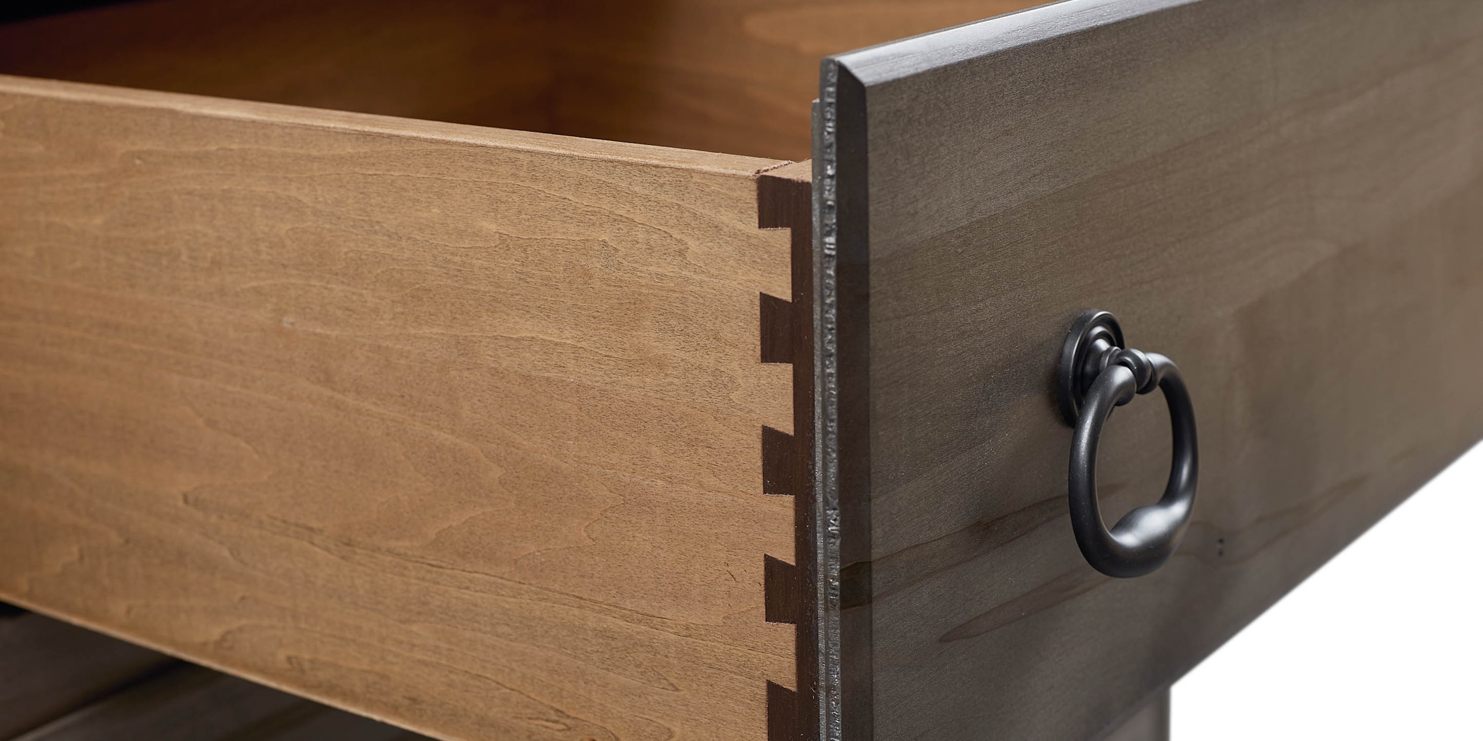 Close-up of the wooden frame and hardware of a chest drawer.
